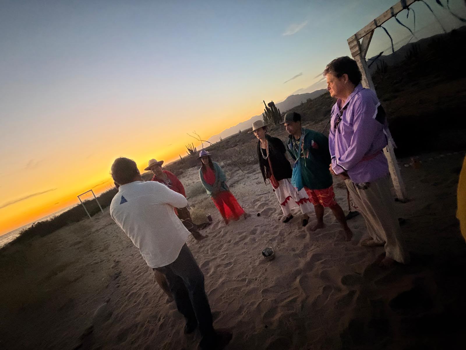 A ceremony circle gathered on the beach at sunset in Desemboque de los Seris