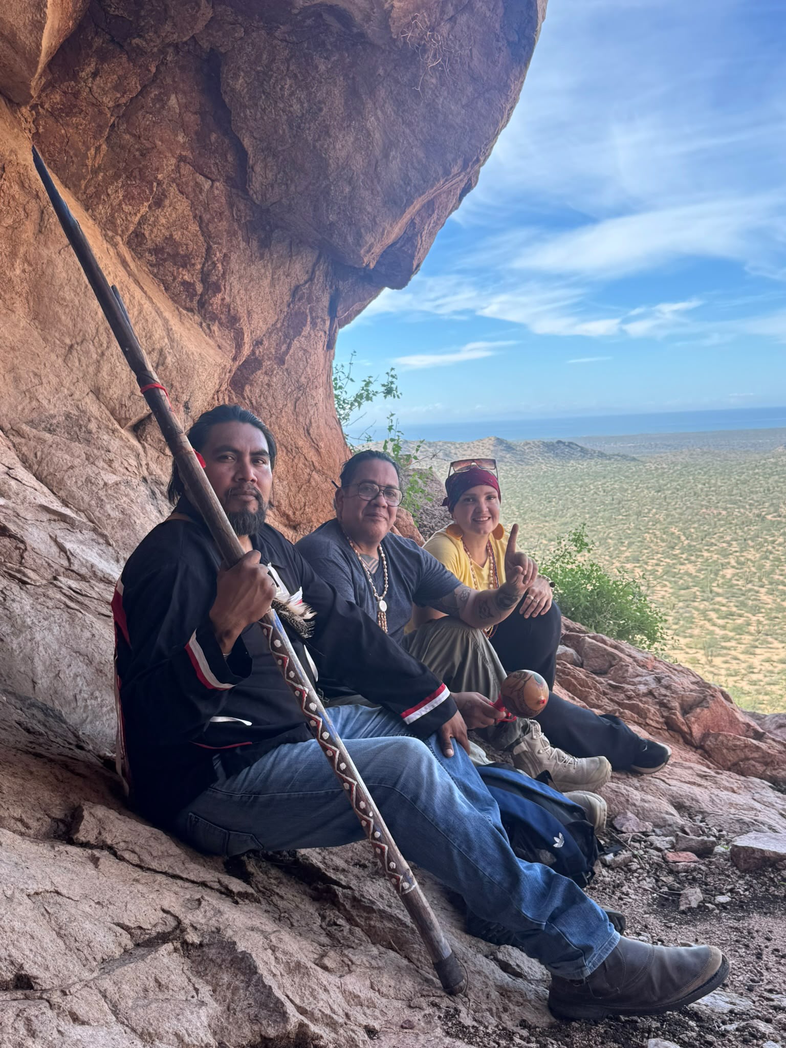 The Comcaac guardians and a seeker gathered under the cave with the desert beyond