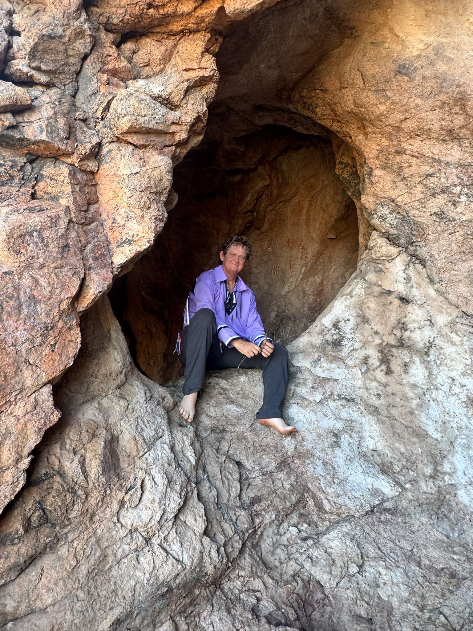 A guardian seated inside the sacred cave beside the ancestral paintings
