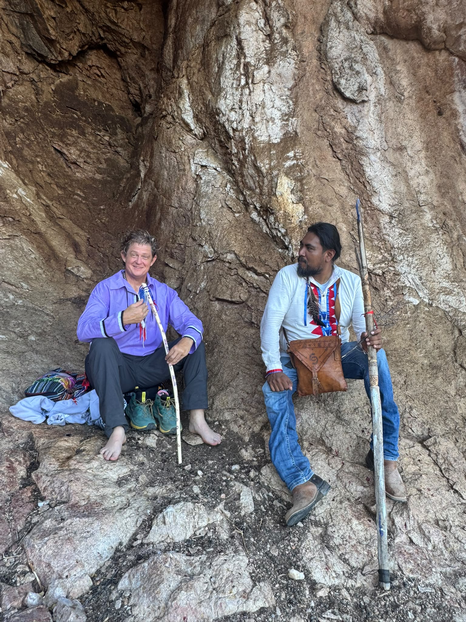 Two guardians resting in the shelter of the cave with ceremonial staffs