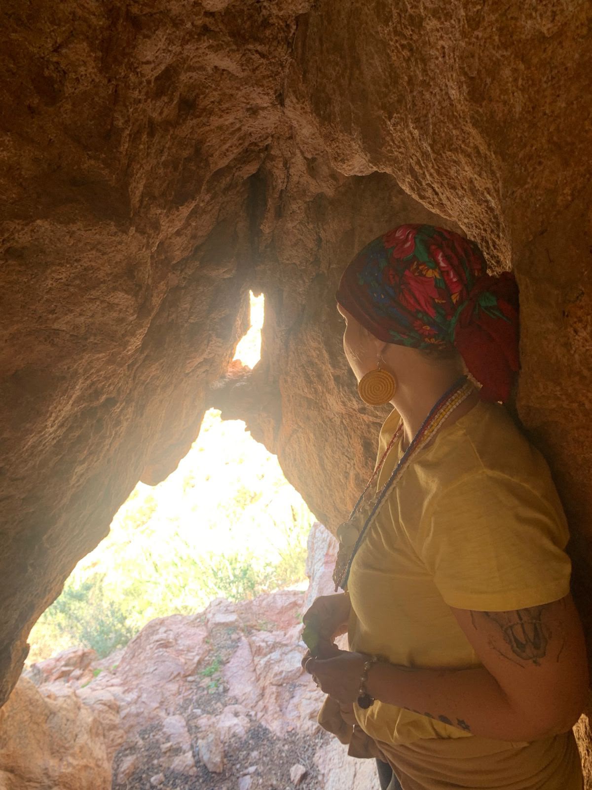 A woman looking out through an opening in the cave toward the light