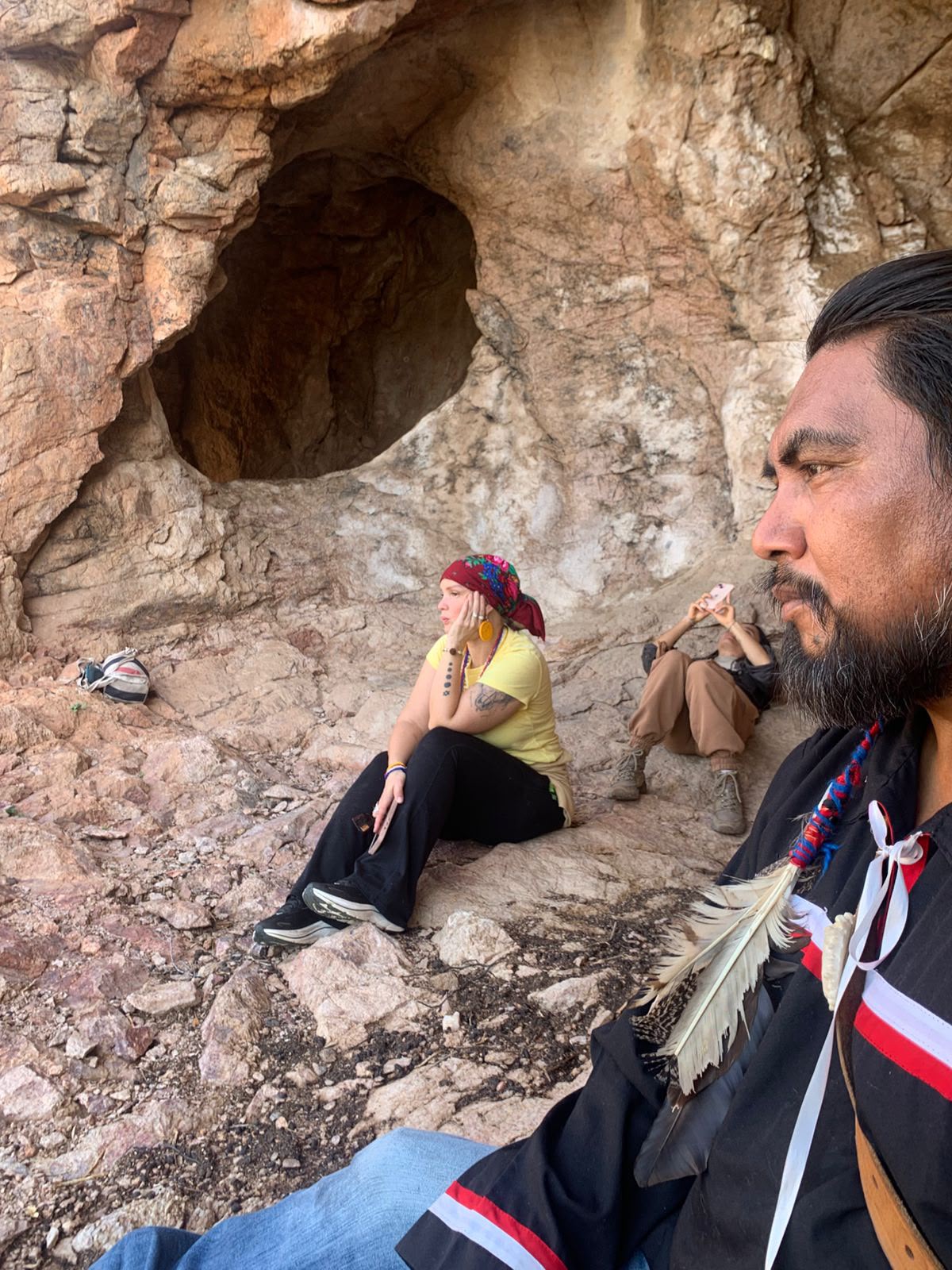 Seekers and a guardian resting at the mouth of the sacred cave