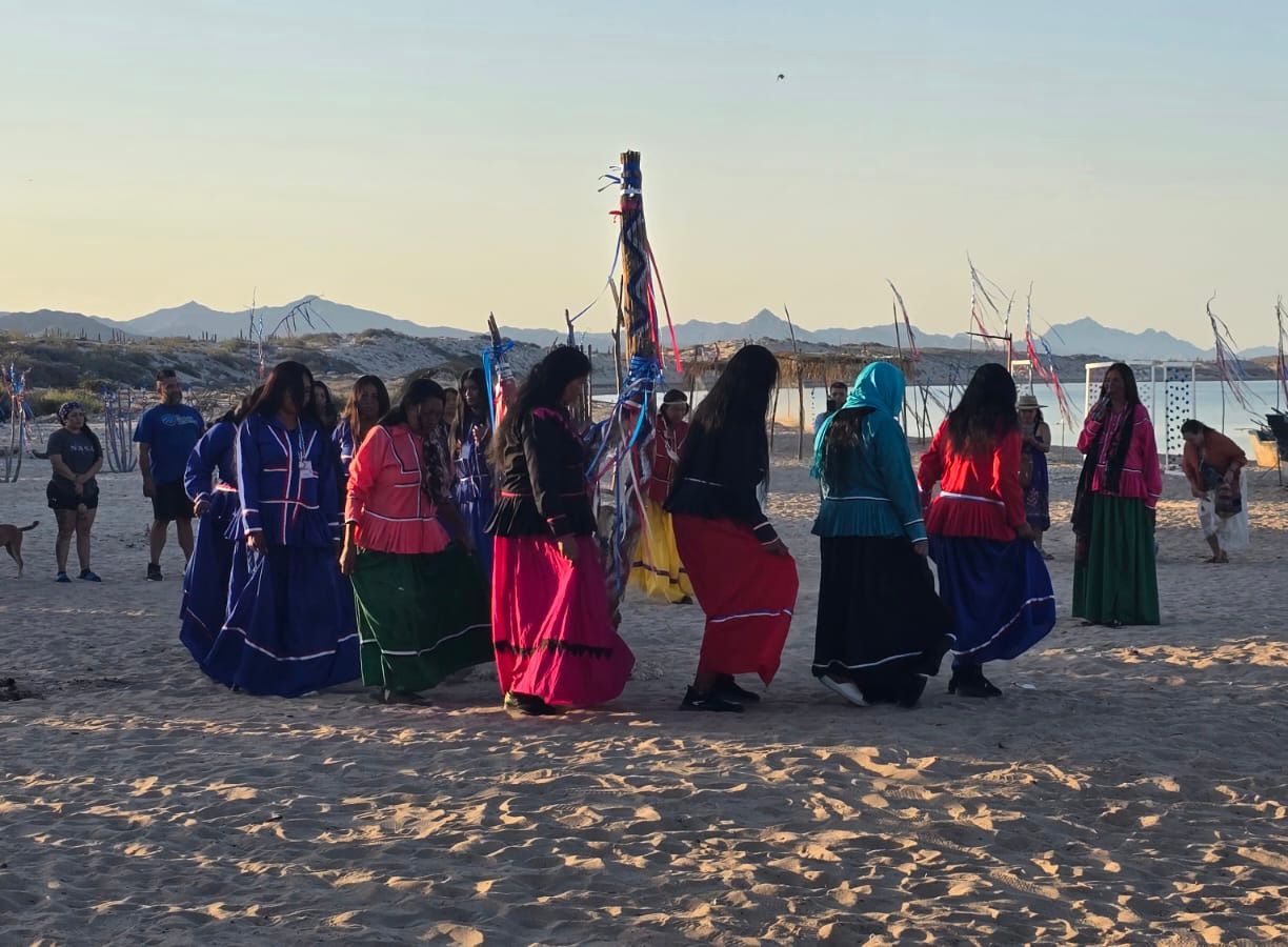 Comcaac women in ceremonial dress dancing on the shore of the Sea of Cortez